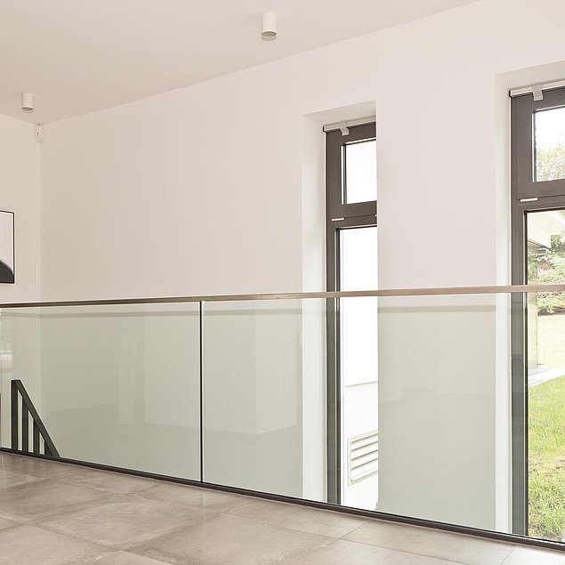 Ganzglasgeländer aus Sicherheitsglas, mit einem oberen U-Profil als Abschluss Bild einer Innentreppe aus feuerverzinktem und pulverbeschichtetem Stahl mit Stufen und Handlauf aus Eiche und Flachstahlgeländer